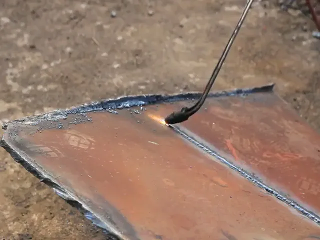 A torch cuts a line through a steel plate on the ground.